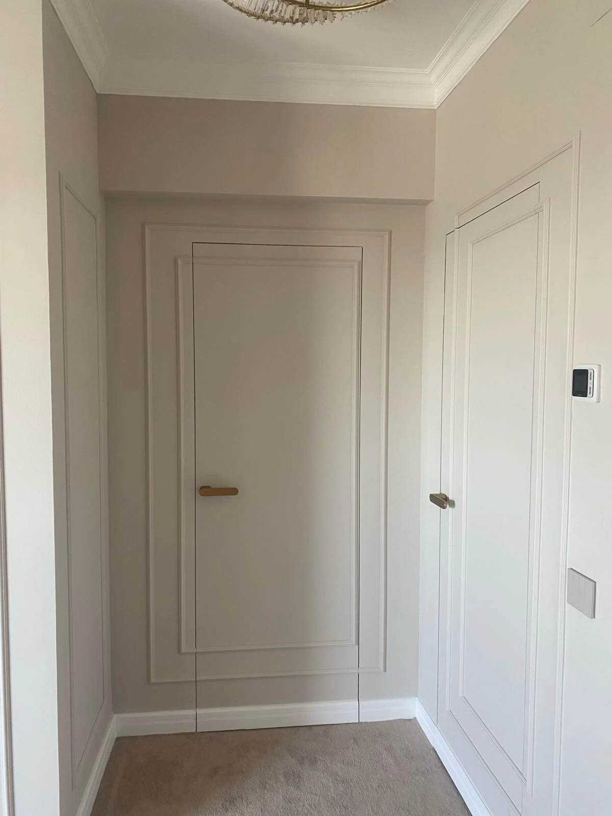 Hol cu două uși filomuro închise în pereți cu profile decorative, unde o foaie întredeschisă ar strica linia