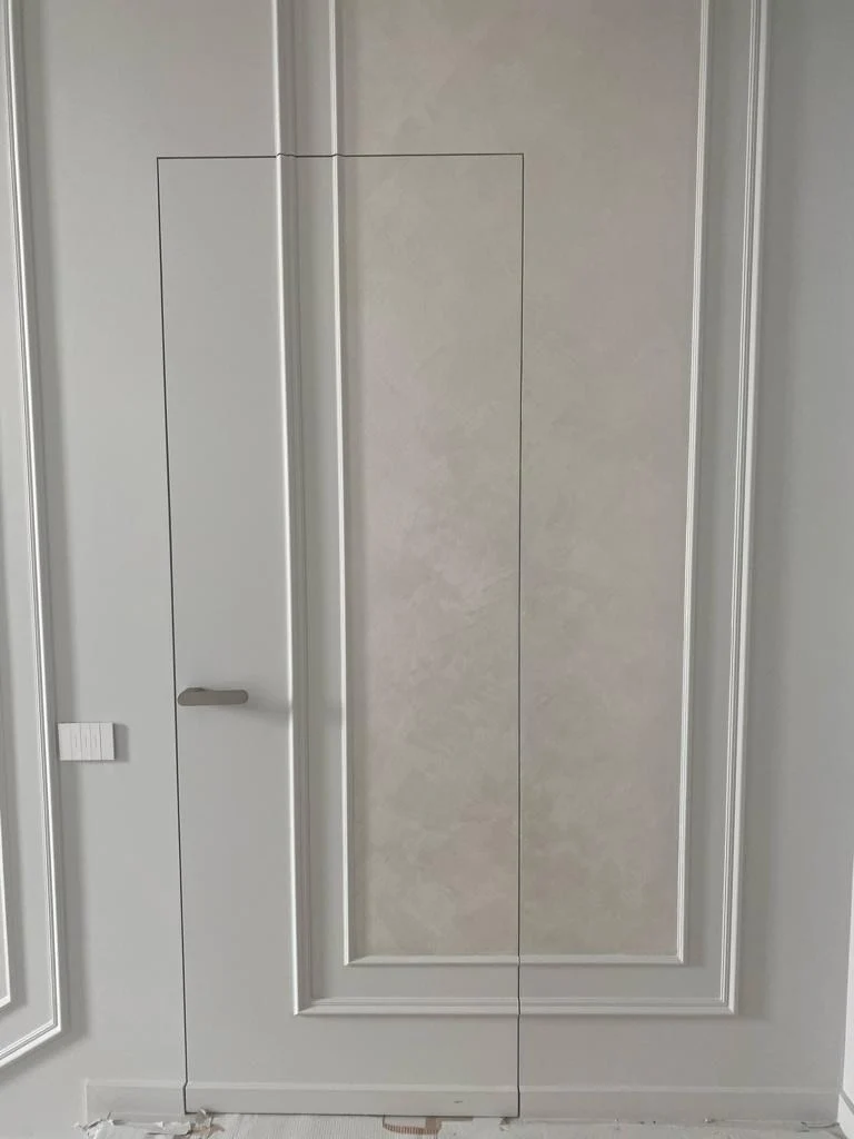 Ușă filomuro închisă, integrată într-un perete cu ramă decorativă, cu mâner discret
