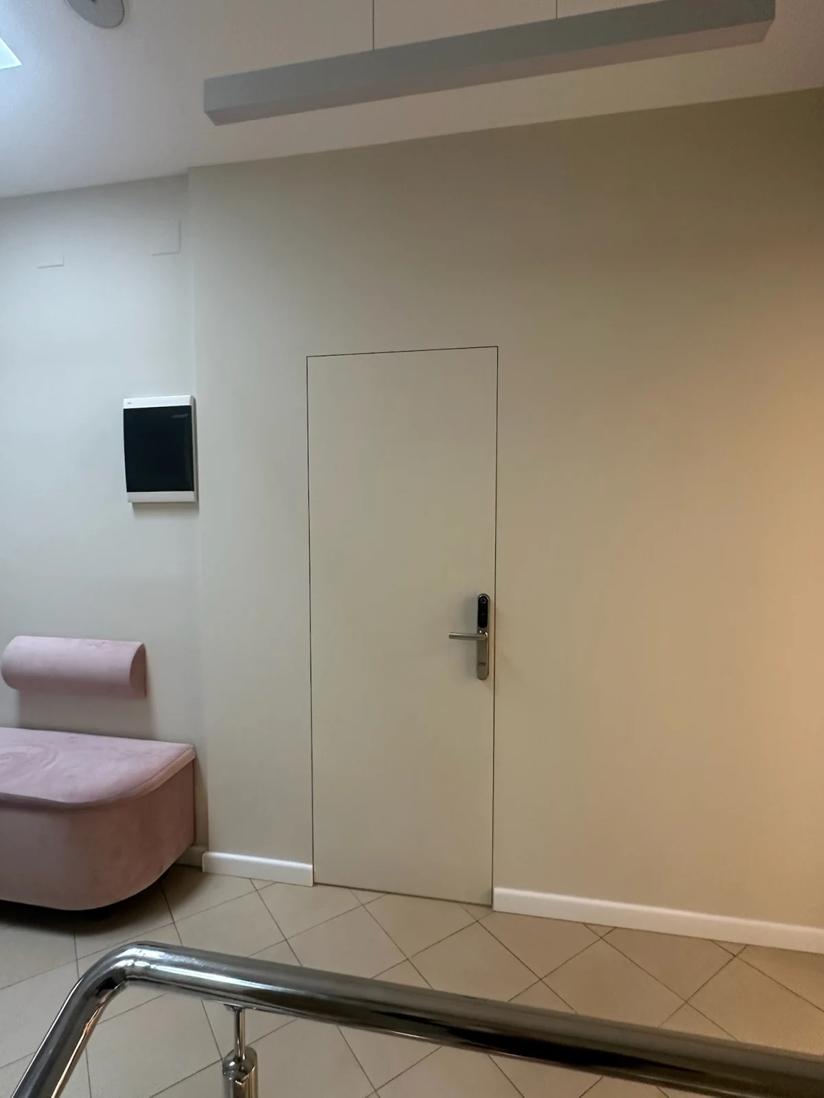 Ușă filomuro într-un spațiu comercial, cu plintă albă aplicată care se întrerupe în dreptul golului