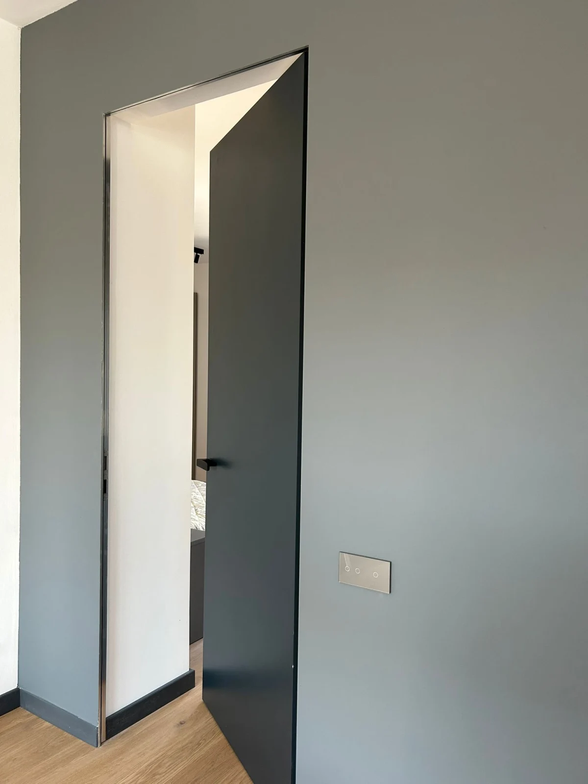 Ușă filomuro gri deschisă, cu tocul aliniat perfect în planul peretelui vopsit